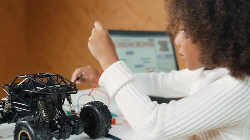 Child Connecting Wires to a Toy Car at Home