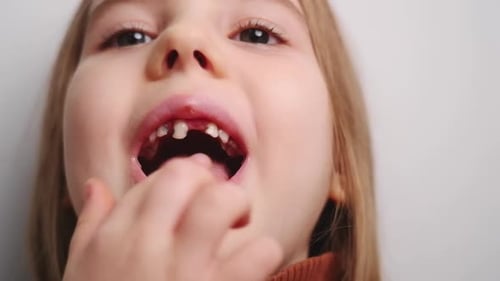 Child Wiggling Loose Tooth with Finger Close Up