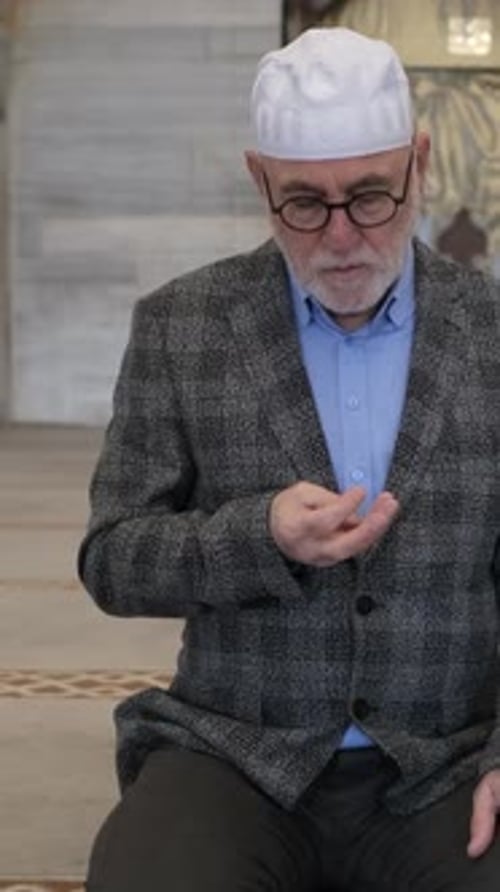 Senior Person Praying with Beads in Mosque