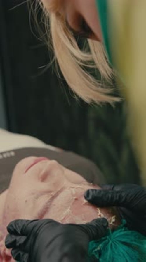 Close-up of a beautician performing a cream peel on a patient's problem skin with acne