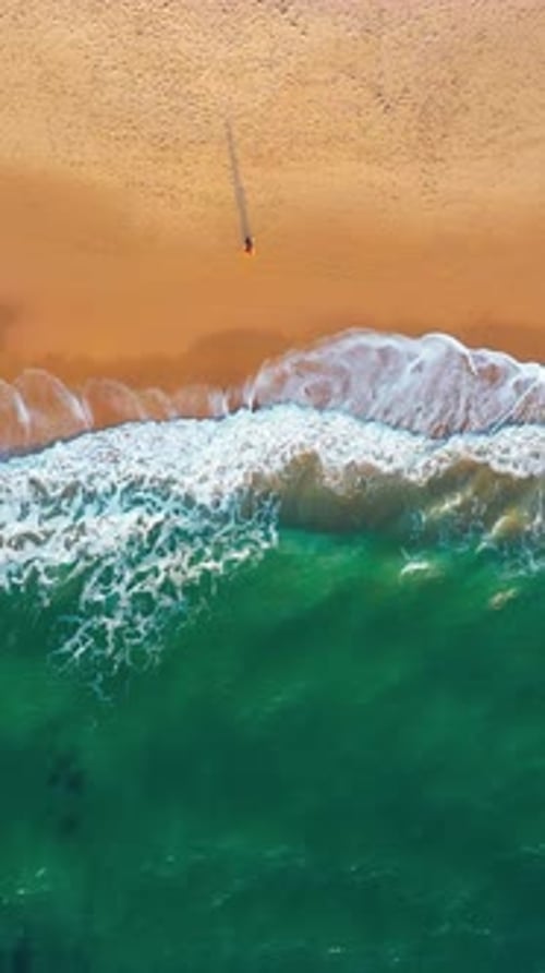 Overhead View of Waves Crashing on Sandy Seashore at Beach