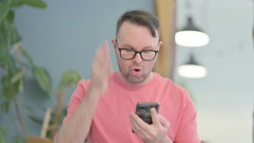 Frustrated Man Scrolling on Smartphone Indoors