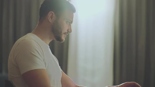 Young Man Typing on Laptop at Home