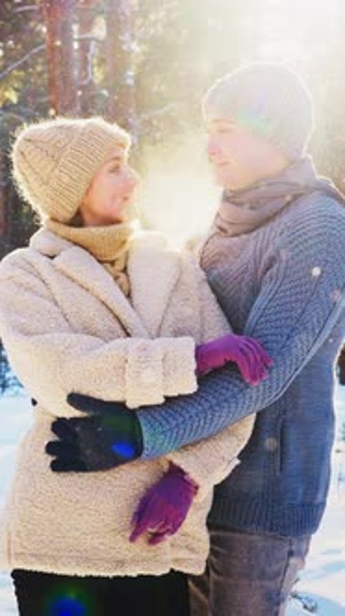 Romantic Winter Moment Between Couple in Snowy Forest at Sunset