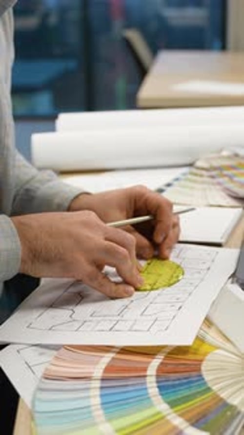 Architect Drawing a House Blueprint with Color Swatches