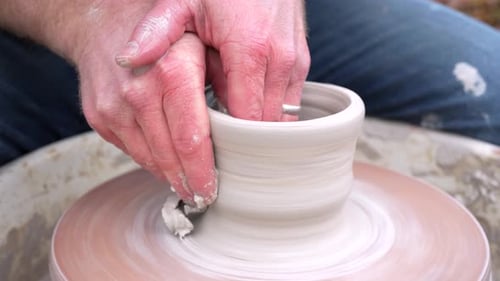 Gros plan des mains d'un potier fabriquant des pots faits à la main sur son tour de poterie. Tirer de l'argile