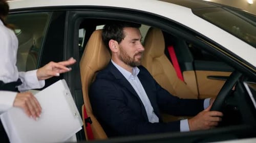Man in Car at Dealership Talking to Saleswoman