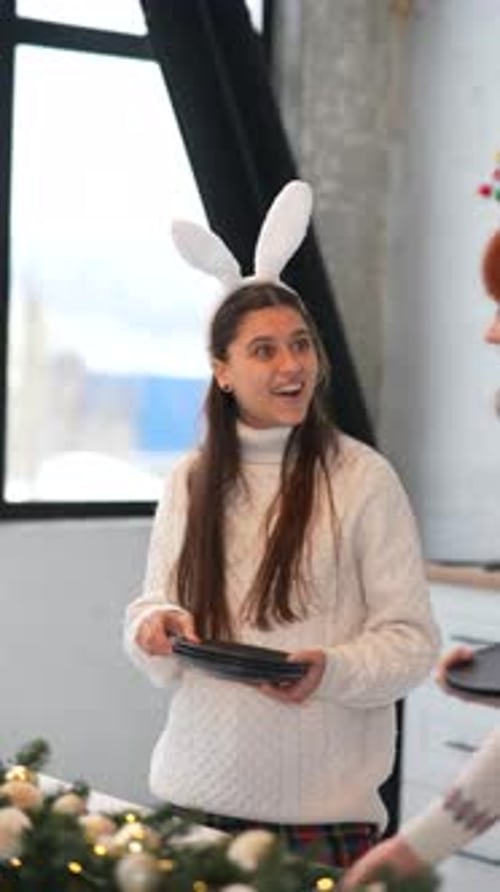 Young Woman Setting Christmas Table with Bunny Ears