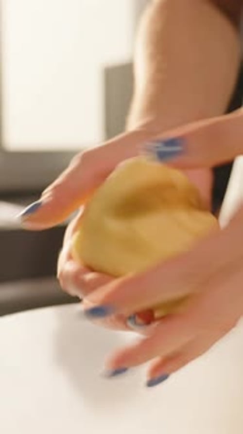 Vidéo verticale. Femme pétrissant de la pâte dans une cuisine lumineuse avec la lumière du soleil de la fenêtre capturée de
près