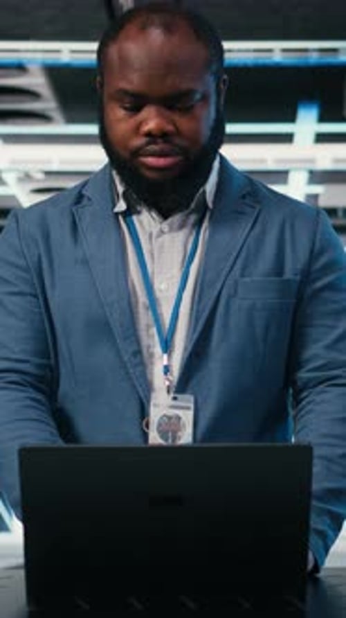 Man Working on Laptop in Server Room