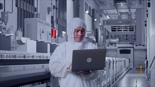 Asiatischer männlicher Wissenschaftler tippt in einer medizinischen Fabrik auf einem Laptop