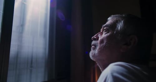 Senior Man Gazing at Bright Window Indoors