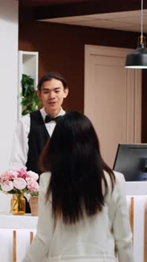 Vertical Video Front Desk Team Staff Welcoming Hotel Guest at Reception