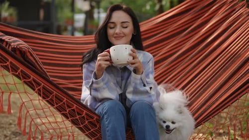 Woman Relaxing in Hammock with Dog and Drink