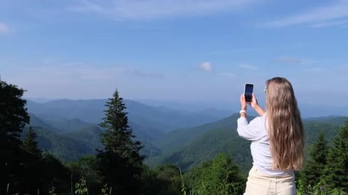 Woman Taking a Photo of Mountain Scenery with Her Phone