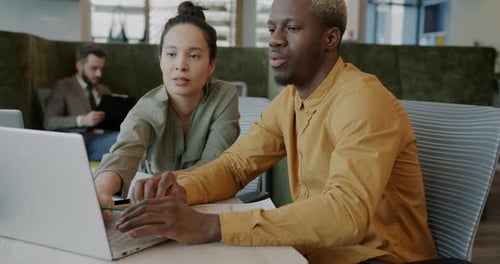 Man and Woman Colleagues Discussing Work and Using Laptop in Office