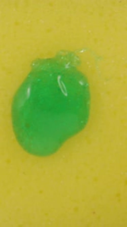 I drip detergent on a yellow sponge, top view. Dolly slider extreme close-up inside. Laowa Probe Ver
