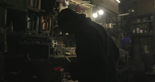 Silhouette of Working Mechanic in Dark Garage Working on Mechanism