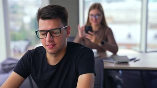 Adult young Caucasian man wearing glasses works at laptop in the office.
