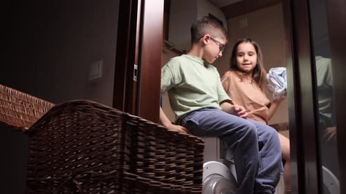 Bruder und Schwester arbeiten zusammen, sortieren Kleidung und erledigen Hausarbeiten in der Waschküche
