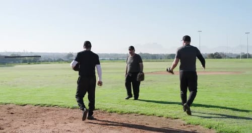 After glove checks and baseball tosses, male teammates practicing catch drill on infield edge