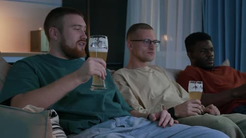Three Friends Toasting with Beer on Couch Indoors