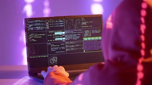 Un hacker en sweat à capuche orange travaille sur un code de terminal avec une projection binaire dans un cyberenvironnement violet