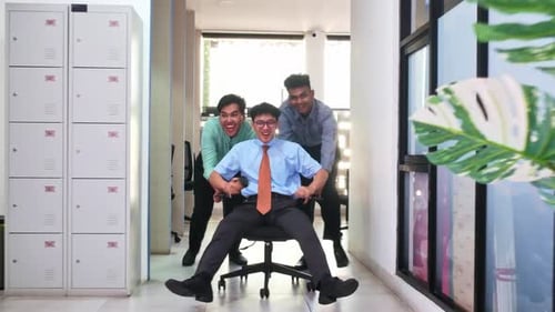 Energetic business team celebrates success with joyful office chair race and high fives