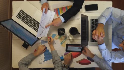 Top View to Male and Female Hands of Managers Examining Financial Graphs at Office Group of