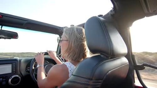 Junge kaukasische Frau genießt auf einem Roadtrip eine sonnige Fahrt in einem Cabrio