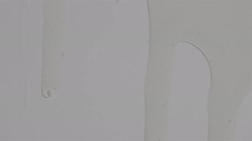Clear Thick And Smooth Liquid Sliding Down On White Flat Surface. Closeup
