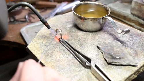 Herstellung von Eheringen aus Gold durch Goldschmied Isolierter Juwelier schmilzt Gold in flüssigem Zustand im Tiegelmakro