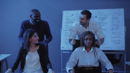 Young Attractive Men Driving on Distillation of Colleagues in Darkened Office Joyful Girls Holding