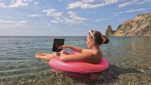 Woman Freelancer Works on Laptop Swimming in Sea on Pink Inflatable Ring Happy Tourist in Sunglasses