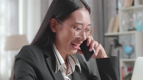 Smiling Woman Talking on Phone Working At Computer