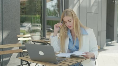 Woman Working at Cafe on Laptop with Notebook