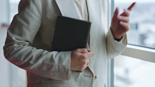 Female hands holding a paper notebook in black cover. Unrecognizable woman opens the book. Close up.