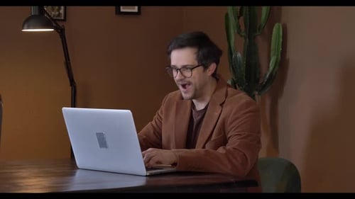Man Celebrating Success While Using Laptop at Desk