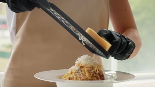 Grating Cheese onto Spaghetti with Black Gloves On