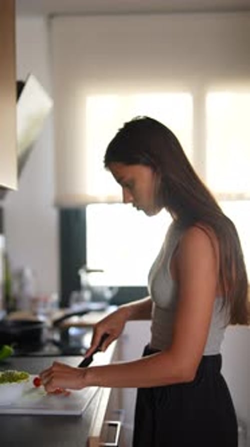 Young Woman Cuts Tomatoes in Kitchen