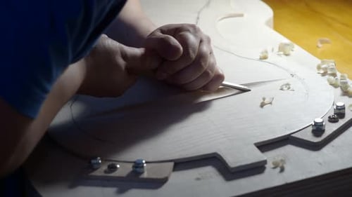 Luthier using chisel while working on violin body in workshop