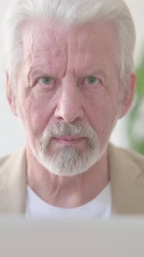 Close Up of Old Man Looking at Camera while using Laptop in Office, Vertical Video
