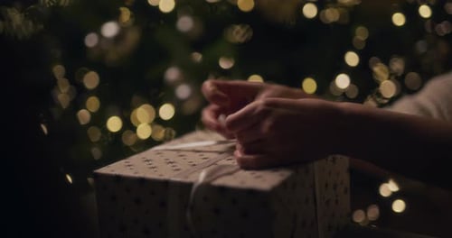 Hands Unwrapping a Present at Christmas Time
