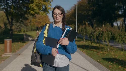 Teenage Girl with Glasses Studying Outdoors in Autumn Park