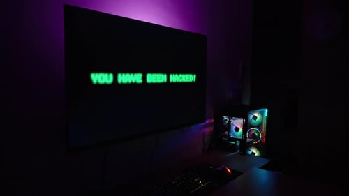 Dark Room with Computer Setup, Monitor Displaying Blinking Green "You Have Been Hacked!" Message,