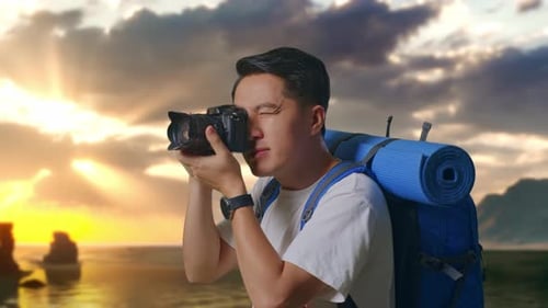 Close Up Side View Of Asian Male Hiker Using A Camera Taking Picture on Beach