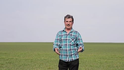 A Front View of a Portrait Happy Owner Farmer in Field Man Speaks in Front of the Camera