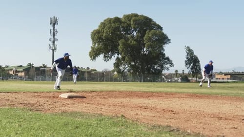 Playing baseball, players running and sliding on field during game