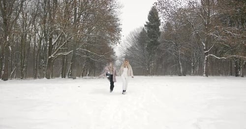 Beautiful Woman Having Fun with Daughter in Winter Forest