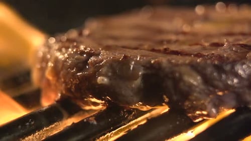 Juicy steak sizzles on hot grill with flames